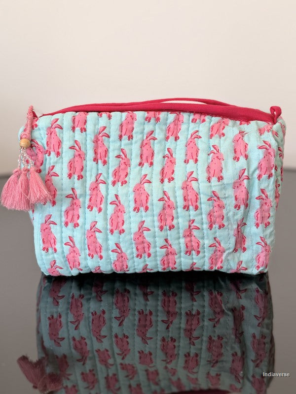 Light blue pouch with pink floral pattern and pink zipper on a reflective surface.