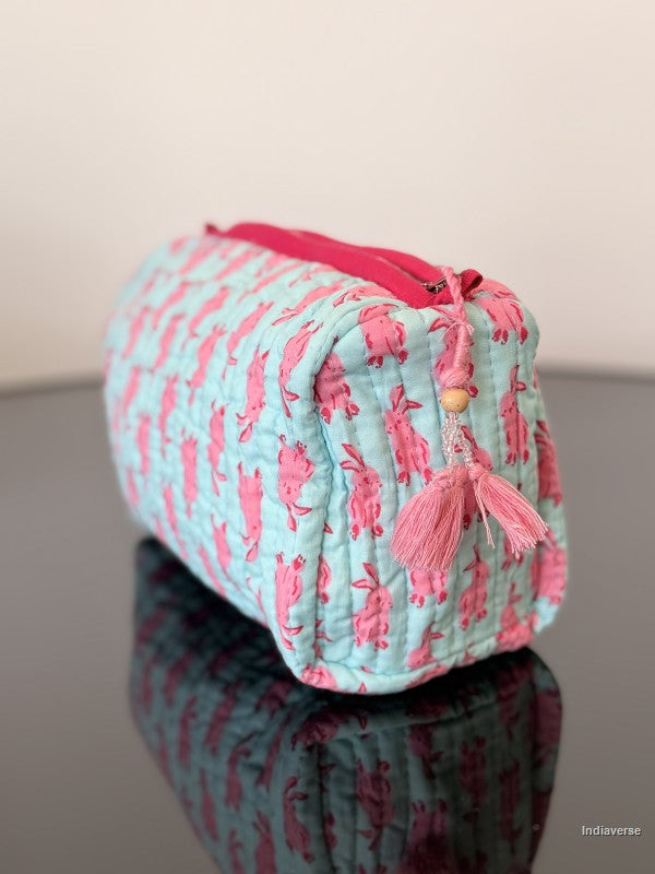 Pink and blue pouch with tassels on a reflective surface