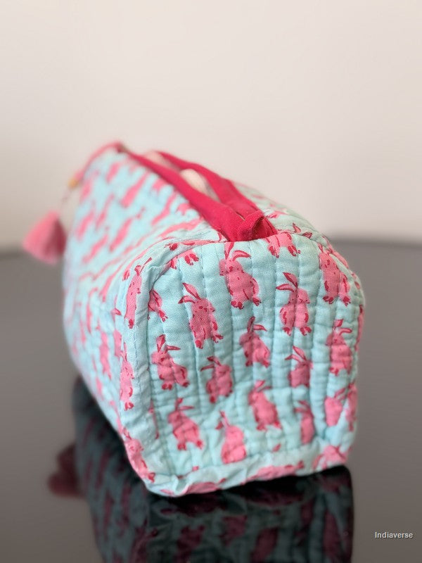 Quilted pouch with pink floral pattern on a reflective surface