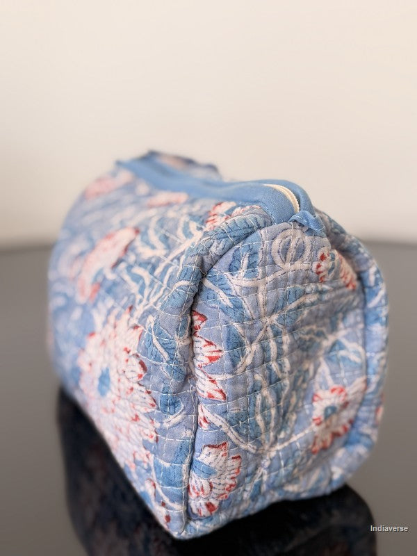 Folded floral quilt with blue and pink pattern on a plain background