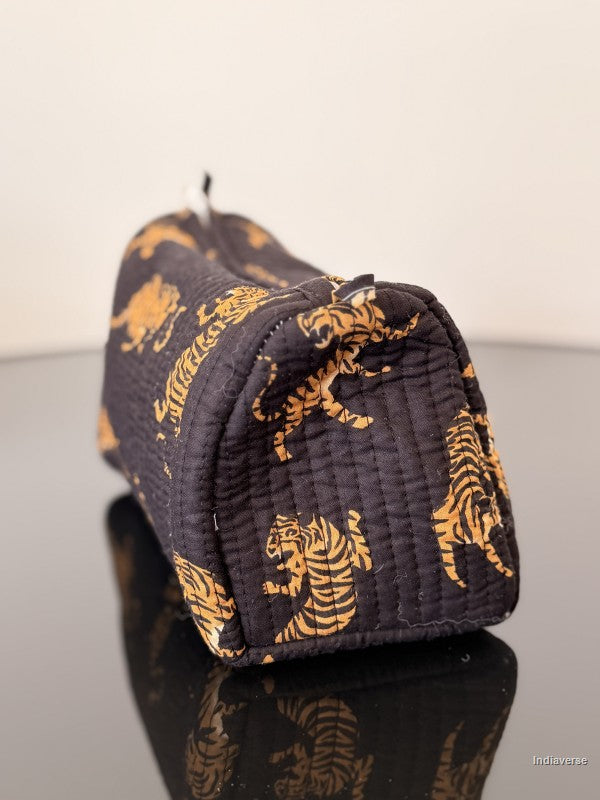 Black pouch with gold tiger patterns on a reflective surface