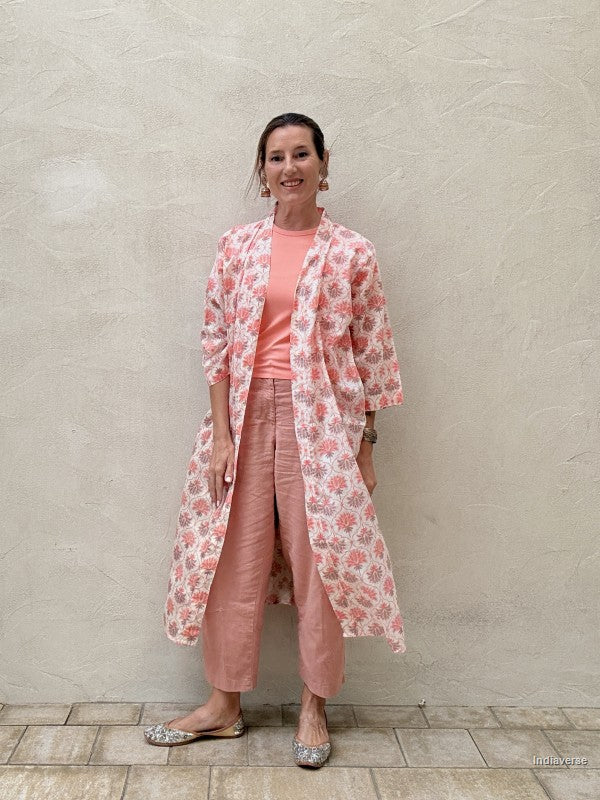 woman wearing a midi size kimono with orange lotus print standing against a beige wall