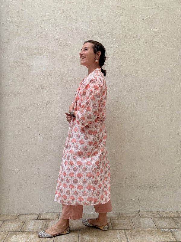 woman wearing a midi size kimono with orange lotus print standing against a beige wall