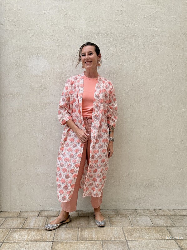 woman wearing a midi size kimono with orange lotus print standing against a beige wall