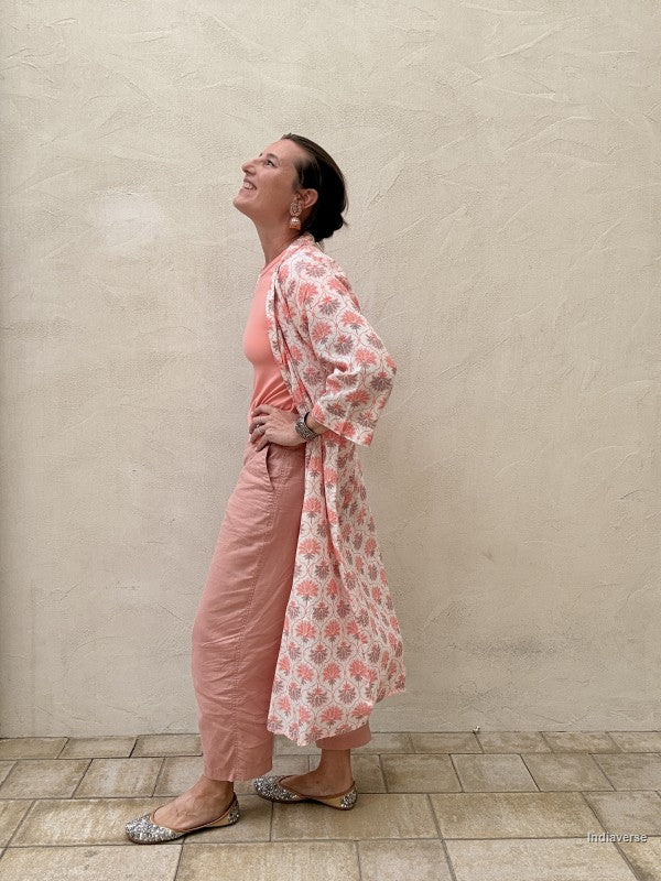 woman wearing a midi size kimono with orange lotus print standing against a beige wall