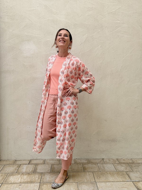 woman wearing a midi size kimono with orange lotus print standing against a beige wall