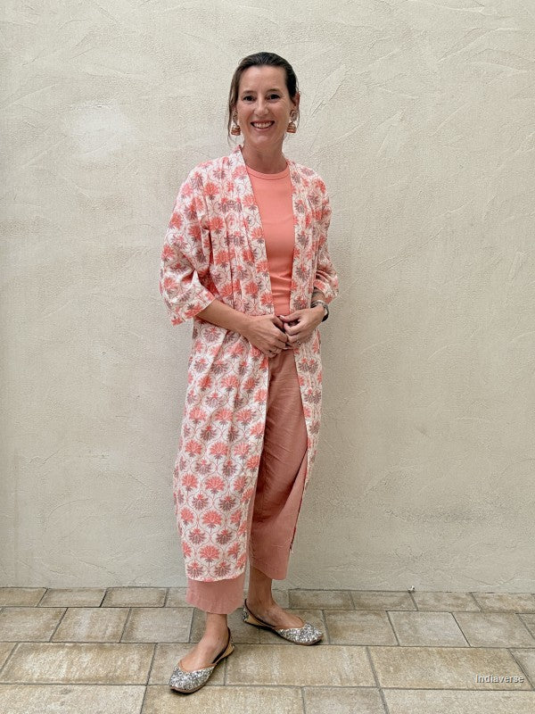 woman wearing a midi size kimono with orange lotus print standing against a beige wall