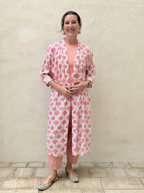 woman wearing a midi size kimono with pink lotus print standing against a beige wall