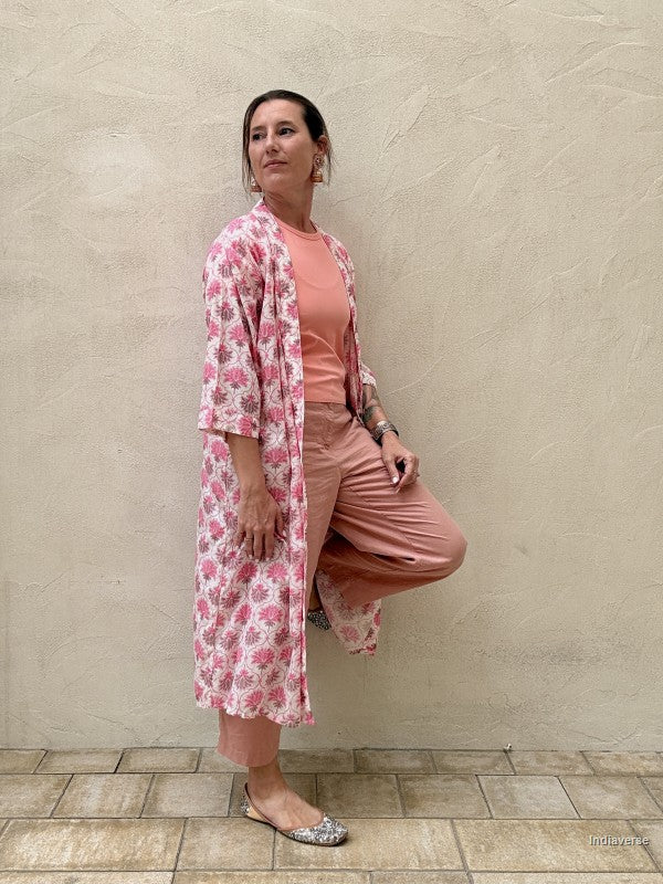 woman wearing a midi size kimono with pink lotus print standing against a beige wall