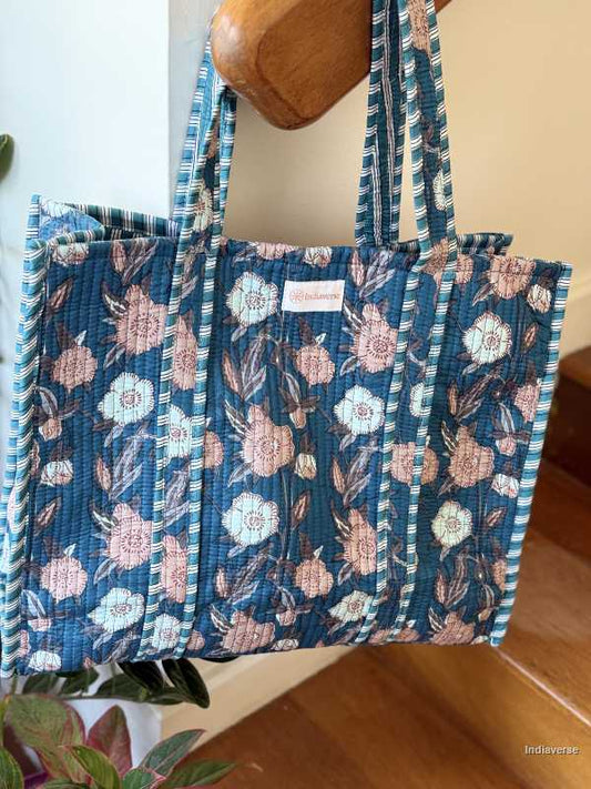 beautiful hand block printed quilted cotton tote bag with pink and off white floral design perfect tot carry all your essentials hanging on wooden staircase railing
