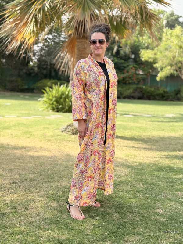 Woman wearing a colorful floral dress standing on grass with trees in the background