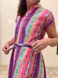 Colorful patterned dress with a belt being worn by a person.