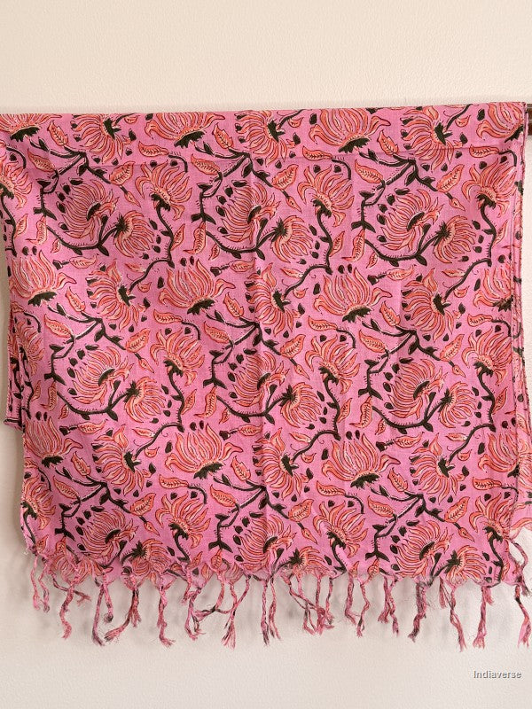 pink cotton scarf with orange floral design hanging from a wooden beam