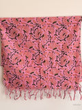pink cotton scarf with orange floral design hanging from a wooden beam