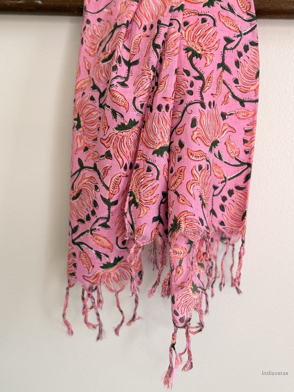 close up of a pink cotton scarf with floral design hanging from a wooden beam