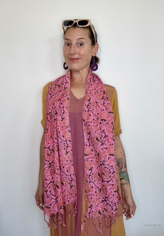 woman wearing a pink cotton scarf standing in front of a white wall