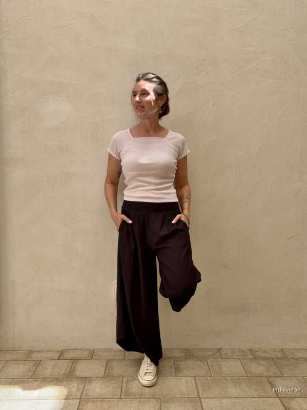 Woman dressed in black pants and light top leaning against beige wall