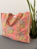 cotton tote bag with leopard design and peach color sitting on a grey surface next to a snake plant
