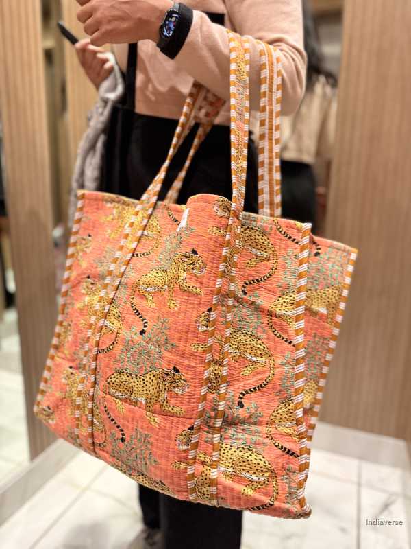 Handbag with a floral pattern held by a person indoors.