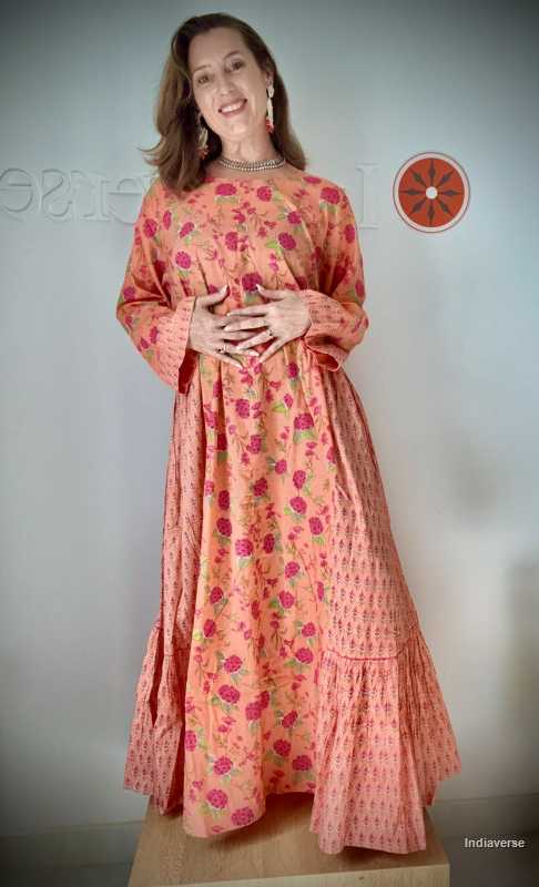 Woman wearing a long, floral-patterned dress against a plain background