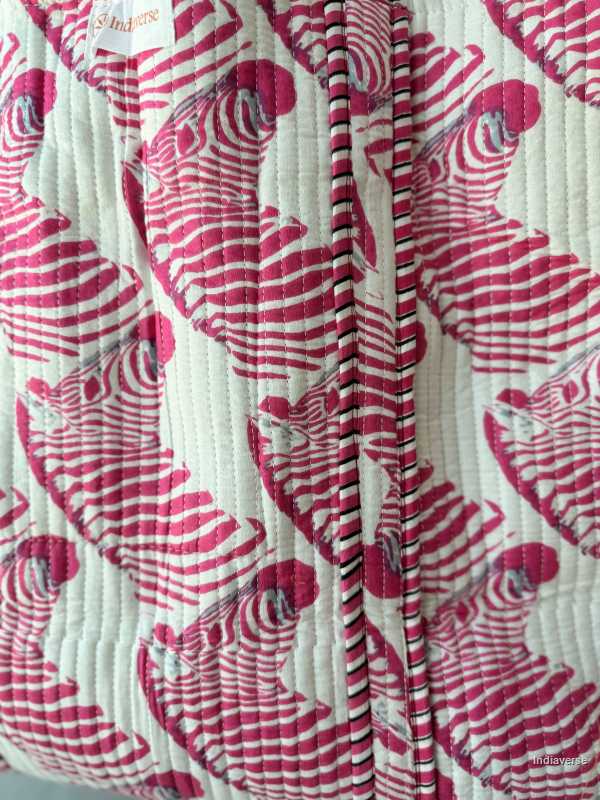 Close-up of a quilt with red and white pattern, brand 'S. Indigo' visible.
