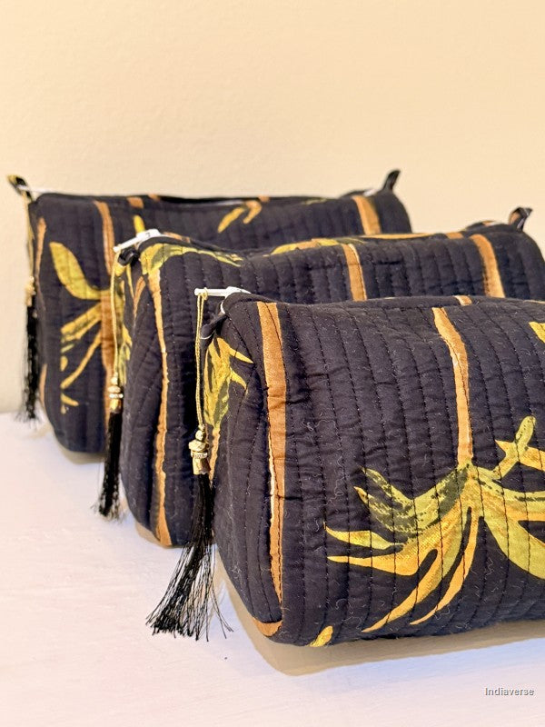 Close up of three toiletry bags with palm tree motif on black with black tassels