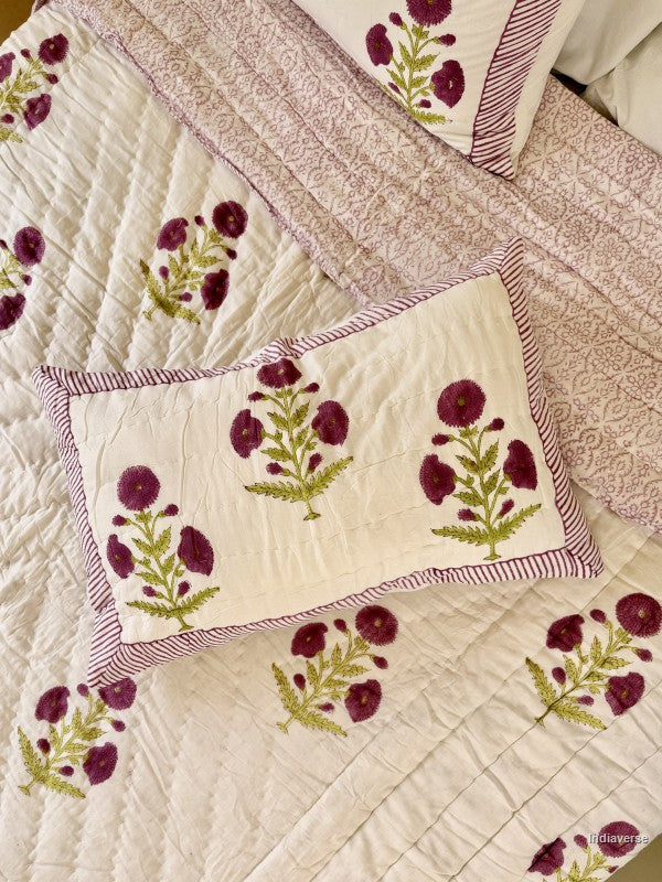 Large white quilted blanket with purple flowers arranged on a white bed in a bedroom with two matching pillowcases