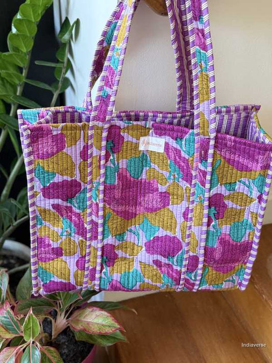 hand block printed quilted cotton tote bag with abstract purple flower design and perfect for shopping and carrying essentials hanging on staircase railing