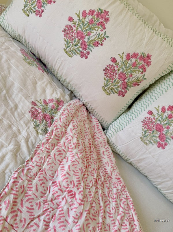 A pink and white floral single quilt spread out and arranged on a white double bed with two matching pillowcases