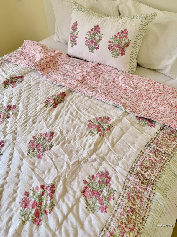 A pink and white floral single quilt spread out on a white double bed with a matching pillowcase in a styled bedroom
