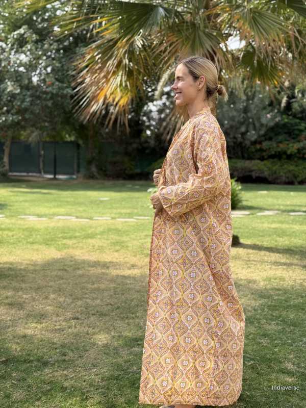Woman in a patterned dress standing outdoors with greenery in the background