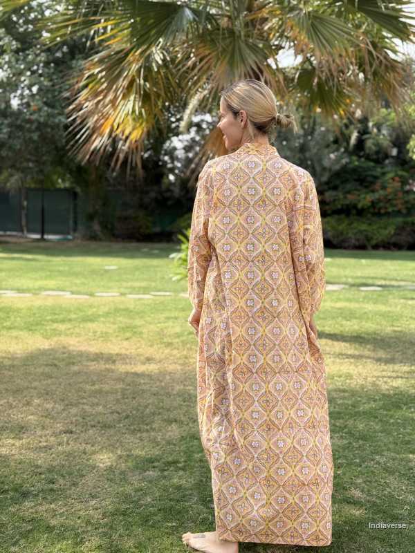 Woman in a patterned dress standing in a grassy area with trees in the background