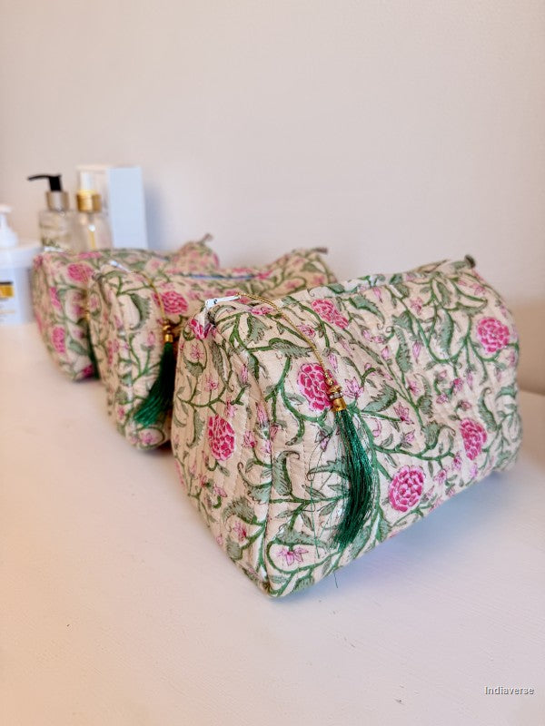 Three fabric cosmetic pouches with a pink and green floral pattern, arranged in a row on a white surface against a light beige wall | Rose Garden Beige