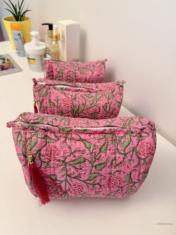 Three pink floral makeup pouches with green and red details, arranged in a row on a white surface with cosmetic bottles in the background | Rose Garden