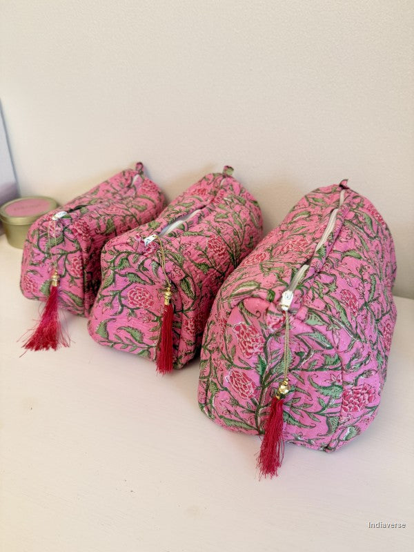 Three pink floral zippered pouches with red tassels arranged on a white surface against a light beige wall | Rose Garden