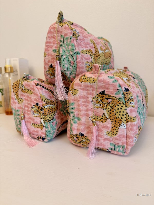 Three pink fabric cosmetic pouches with a leopard print pattern and pink tassels, arranged on a light surface against a plain light background | Rose Leopard