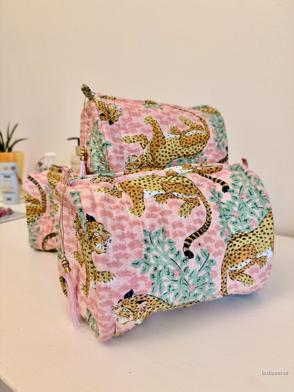Three matching fabric cosmetic pouches with a pink leopard print and green foliage pattern, displayed on a light surface against a plain wall | Rose Leopard