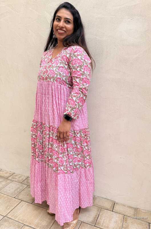 Woman wearing a pink floral dress standing against a beige wall.