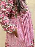 Woman wearing a pink floral dress with long sleeves against a beige background