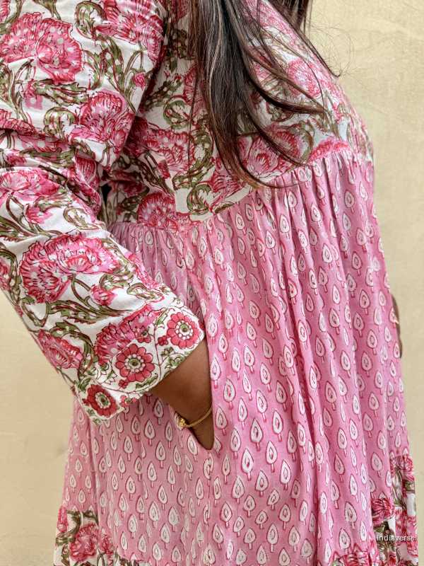 Woman wearing a pink floral dress with long sleeves against a beige background