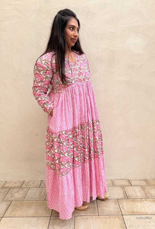 Woman wearing a pink floral dress standing against a beige wall.