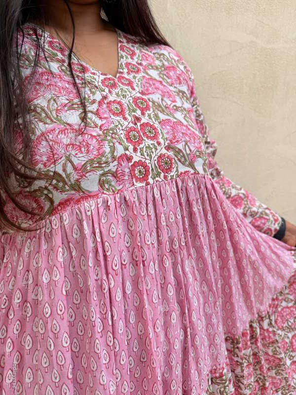 Person wearing a pink floral saree with a beige background