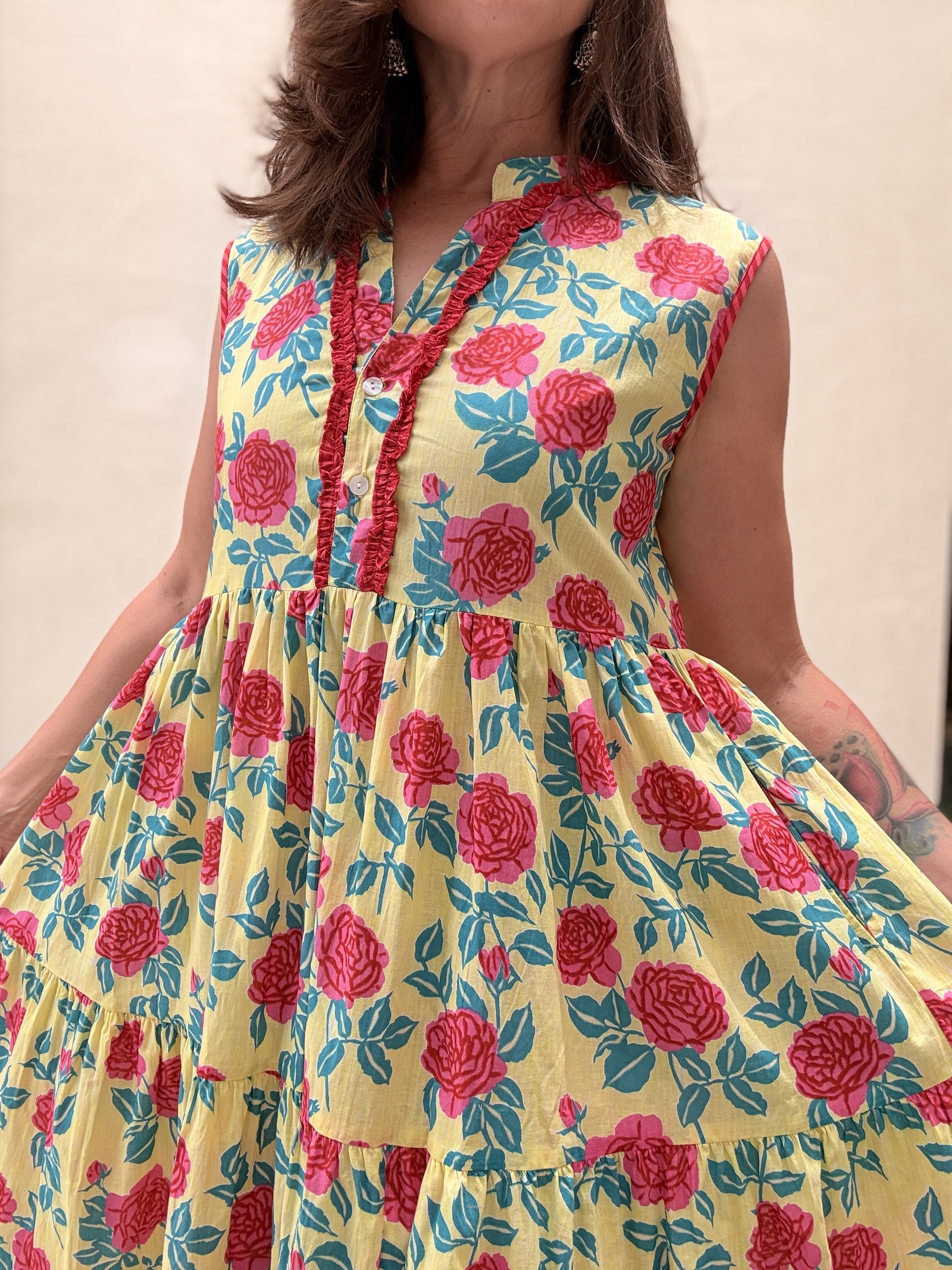 Woman wearing a yellow dress with red floral pattern