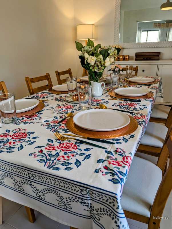 Dining table set with a floral rose tablecloth in a kitchen setting