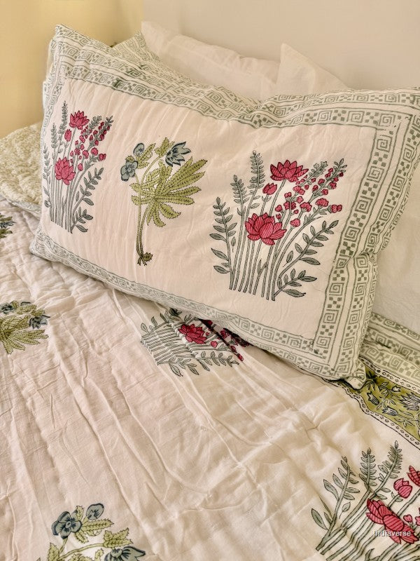 Single cotton quilt with two matching pillow cases and red flower design arranged on a white bed frame