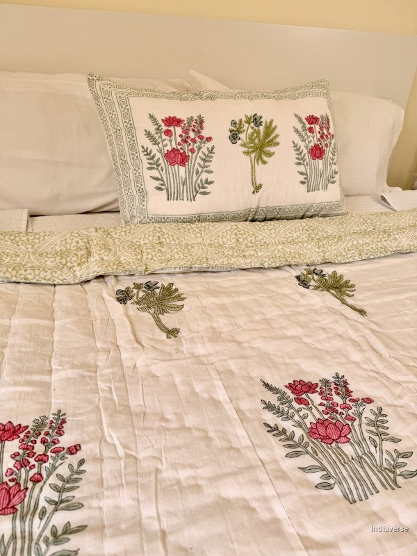 Single cotton quilt with two matching pillow cases and red flower design arranged on a white bed frame