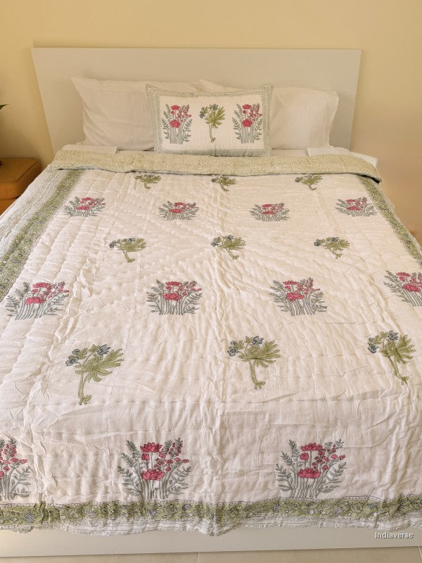 Single cotton quilt with two matching pillow cases and red flower design arranged on a white bed frame