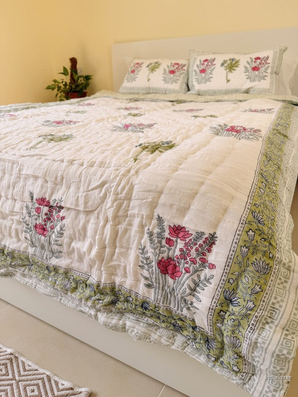 Single cotton quilt with two matching pillow cases and red flower design arranged on a white bed frame