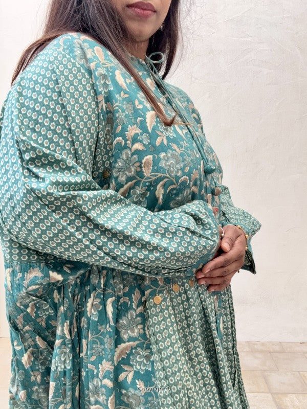 Woman wearing a teal floral dress against a white background