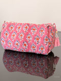 Pink patterned pouch with tassel on a reflective surface